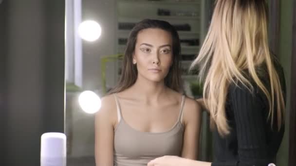 Artista de maquillaje haciendo peinado para mujer asiática con aceite en salón de belleza — Vídeo de stock