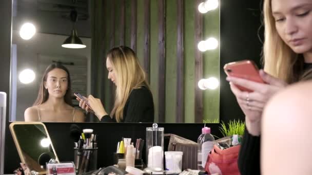 Brunetky asijské žena s make-up sedí v salonu krásy před zrcadlem — Stock video