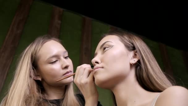 Visagiste Kaukasia menarik melakukan makeup untuk perempuan muda di salon kecantikan — Stok Video