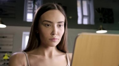 Yaratıcı makyajlı genç esmer güzel kadın kuaförde aynaya bakıyor.