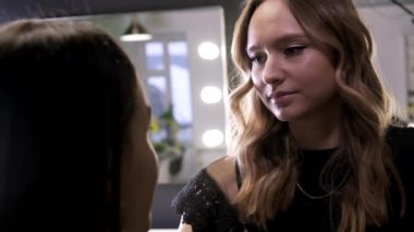 Makyaj sanatçısı güzellik salonunda genç Asyalı çekici bir kadın için makyaj yapıyor.