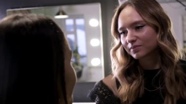 Makyaj sanatçısı güzellik salonunda genç Asyalı çekici bir kadın için makyaj yapıyor.