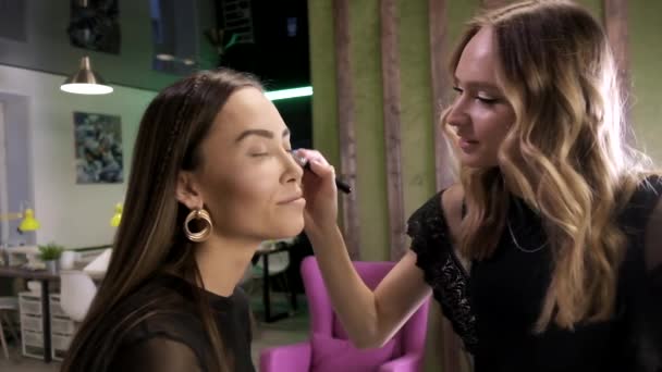Maquiagem artista fazendo maquiagem para atraente jovem asiático feminino no salão de beleza — Vídeo de Stock