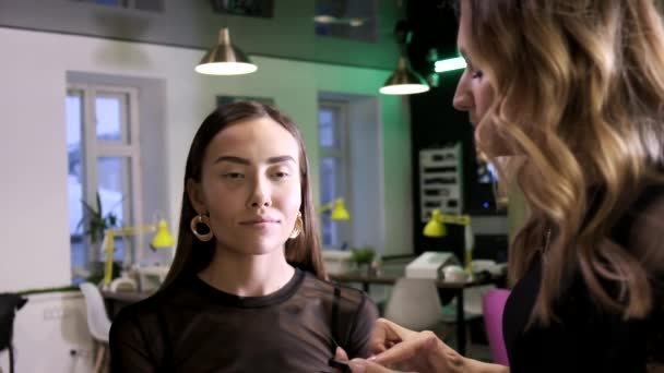 Makeup artist κάνει μακιγιάζ για ελκυστική νεαρή ασιάτισσα στο σαλόνι ομορφιάς — Αρχείο Βίντεο