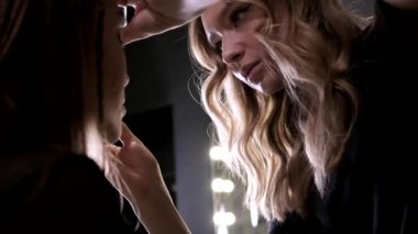 Makyaj sanatçısı güzellik salonunda genç Asyalı çekici bir kadın için makyaj yapıyor.