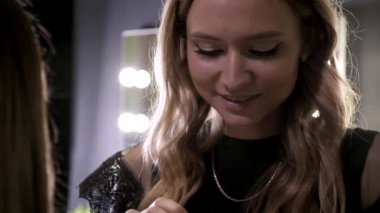 Makyaj sanatçısı güzellik salonundaki çekici esmer kızın makyajını yapıyor.