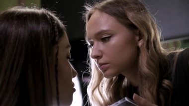 Makyaj sanatçısı güzellik salonundaki çekici esmer kızın makyajını yapıyor.