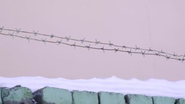 Tuğla çitin üzerinden pembe duvara karşı dikenli teller. Hapis, hapis
