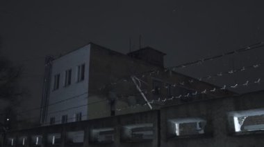 Soğuk, karanlık kış gecesinde, kar yağarken beton çitin üzerinden dikenli teller örülmüş.