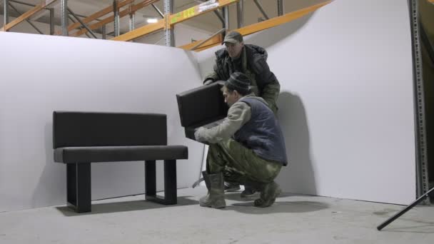РОССИЯ, ВЛАДИМИР, 30 МАР 2021: два работника-мужчины разбирают диван на складе — стоковое видео