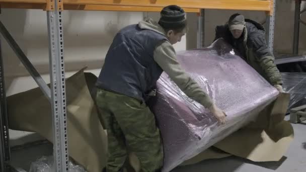 RUSSIA, VLADIMIR, 30 MAR 2021: dua pria bergerak sofa dikemas di gudang — Stok Video