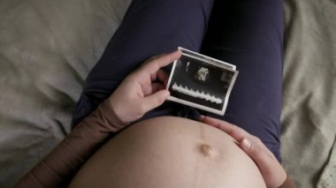 Koca göbekli hamile bir kadının evde ultrason taramasına bakmasını bekliyorum.