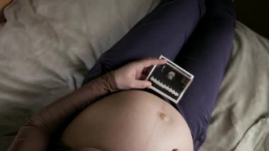 Koca göbekli hamile bir kadının evde ultrason taramasına bakmasını bekliyorum.