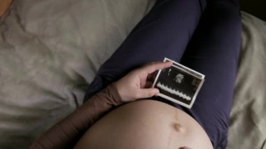 Koca göbekli hamile bir kadının evde ultrason taramasına bakmasını bekliyorum.