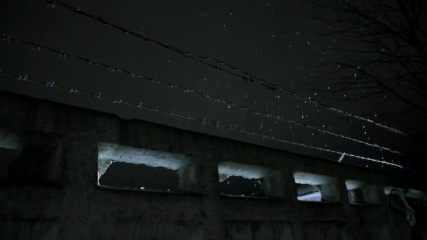 Gefängnis Stacheldraht über Betonzaun in der kalten dunklen Winternacht bei Schneefall — Stockvideo