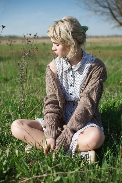 Joven atractivo caucásico hembra sentado en un suelo en el campo en día soleado — Foto de Stock