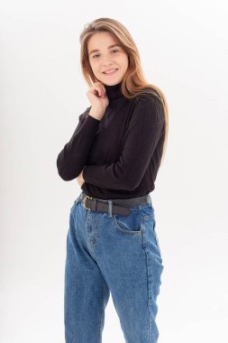 Uzun saçlı, siyah balıkçı yakalı, kot pantolonlu, beyaz bir kadın.