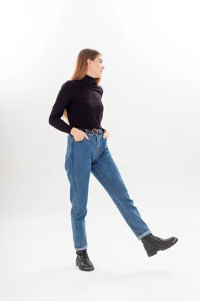 Молодая привлекательная белая женщина с длинными волосами в черной водолазке, синих джинсах — стоковое фото