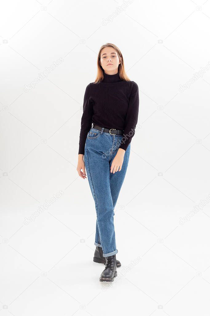 young attractive caucasian woman with long hair in black turtleneck, blue jeans