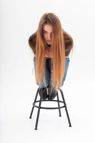 Flaco caucásico bonita hembra en negro cuello alto, azul jeans se inclina en taburete —  Fotos de Stock