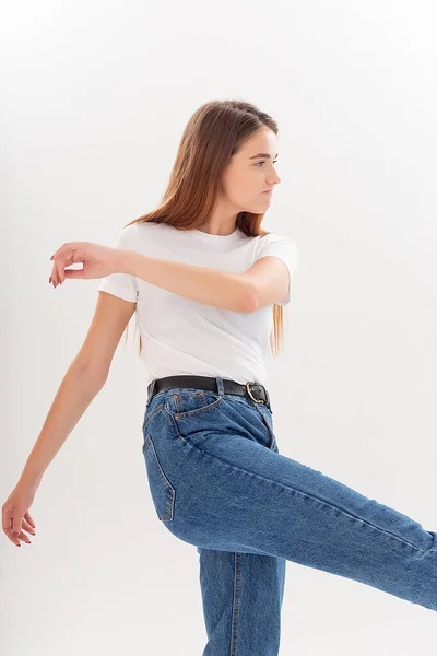 Joven caucásico bonita chica con el pelo largo en camiseta, pantalones vaqueros azules en el estudio — Foto de Stock