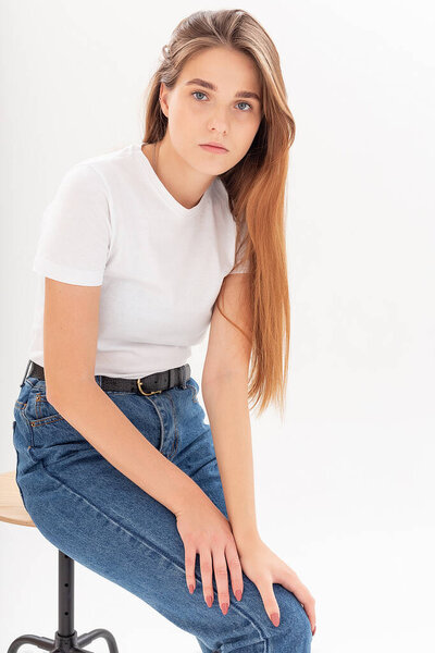 young caucasian pretty girl with long hair in t-shirt, blue jeans at studio