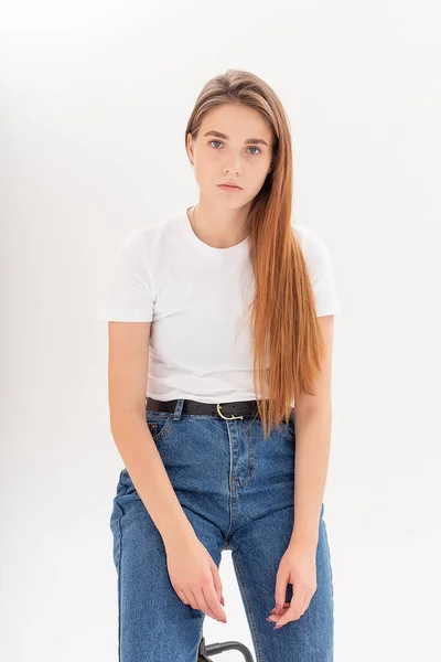 Ung kaukasiska söt flicka med långt hår i t-shirt, blå jeans på studio — Stockfoto