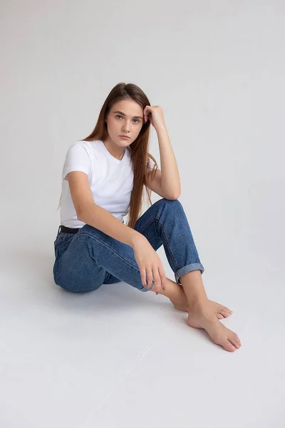 Uzun saçlı, uzun saçlı, stüdyoda kot pantolon giyen beyaz bir kız.