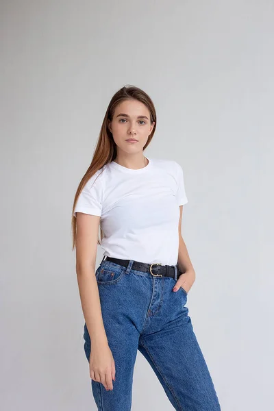 Jovem caucasiano menina bonita com cabelos longos em t-shirt, jeans azuis no estúdio — Fotografia de Stock