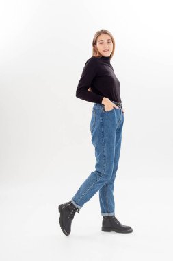 Uzun saçlı, siyah balıkçı yakalı, kot pantolonlu, beyaz bir kadın.