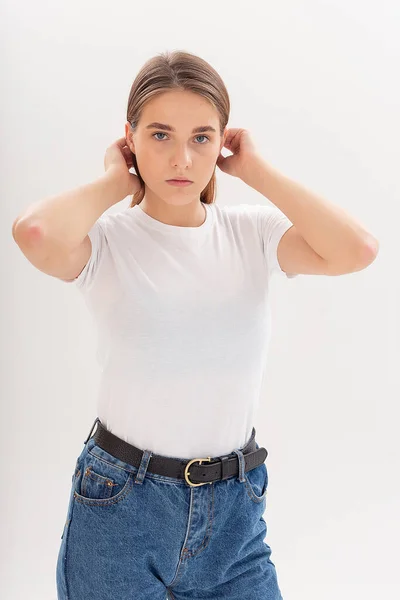 Ung kaukasiska söt flicka med långt hår i t-shirt, blå jeans på studio — Stockfoto
