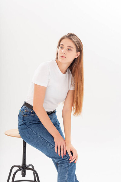 young caucasian pretty girl with long hair in t-shirt, blue jeans at studio