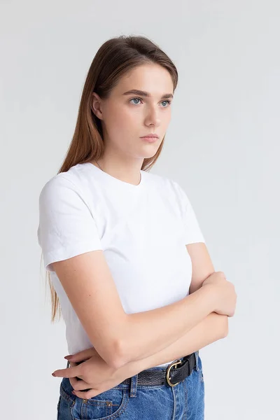 Młoda biała ładna dziewczyna z długimi włosami w t-shirt, niebieskie dżinsy w studio — Zdjęcie stockowe
