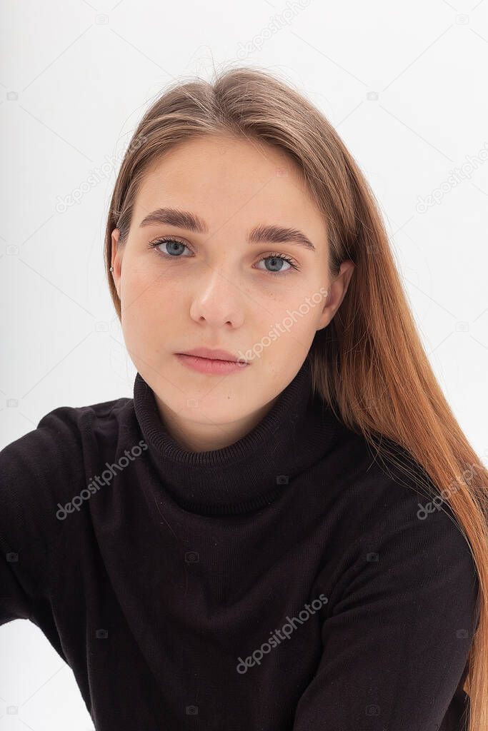 young caucasian pretty girl with long hair in black turtleneck at white studio