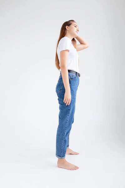 Joven caucásico bonita chica con el pelo largo en camiseta, pantalones vaqueros azules en el estudio — Foto de Stock