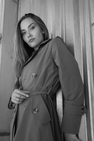 Приваблива молода азіатська модель в сірому траншеї пальто, що стоїть біля стіни на відкритому повітрі — стокове фото