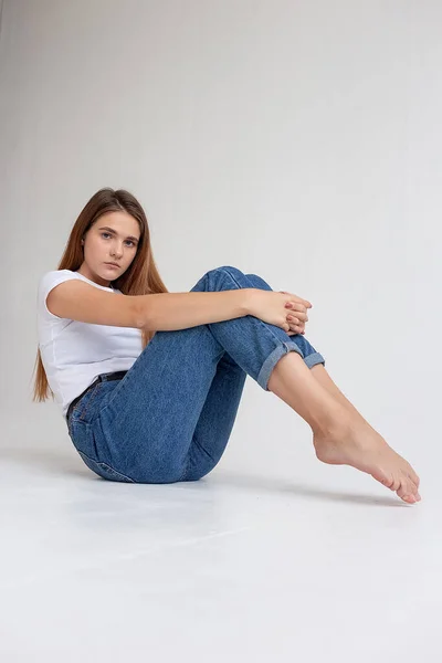 Jeune caucasienne jolie fille aux cheveux longs en t-shirt, jeans bleus au studio — Photo