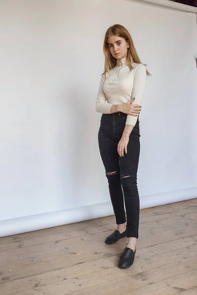 Portret młodej przemyślanej nastolatki modelki w białym swetrze i czarnych dżinsach — Zdjęcie stockowe