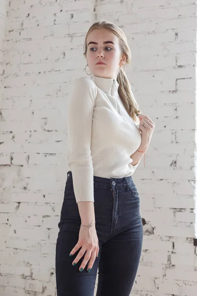 Potret muda model remaja bijaksana mengenakan sweater putih dan celana jeans hitam — Stok Foto