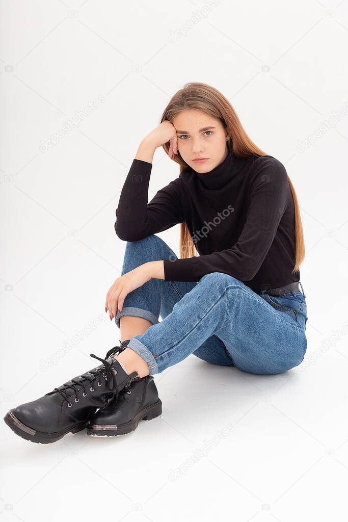 young attractive caucasian woman in black turtleneck, blue jeans at white studio