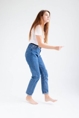 Beyaz stüdyo arka planında çıplak ayakla dans eden beyaz tenli güzel bir kadın.