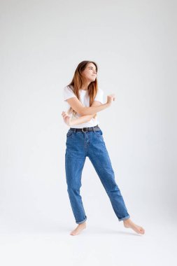 Beyaz stüdyo arka planında çıplak ayakla dans eden beyaz tenli güzel bir kadın.