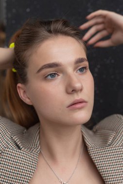 Uzun saçlı, mavi gözlü, ceketli, beyaz bir kadın.