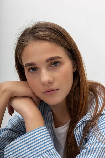 Fiatal fehér csinos lány hosszú haj kék csíkos ing ül a stúdióban — Stock Fotó