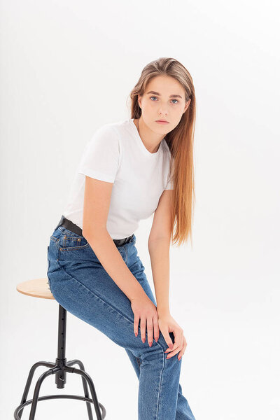 young caucasian pretty girl with long hair in t-shirt, blue jeans at studio