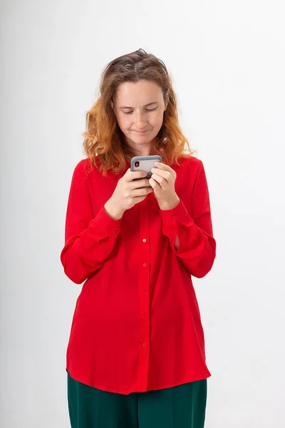 Genç, konsantre olmuş, kızıl saçlı, cep telefonu kullanan, internette sohbet eden bir kadın. — Stok fotoğraf