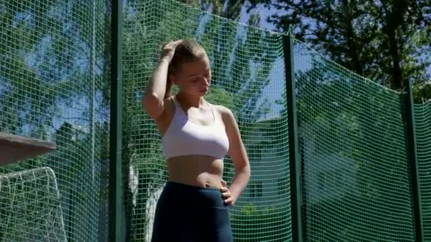 Fiatal fitt szőke busty nő sportruházat kinyújtja a nyakát a sportpályán — Stock videók