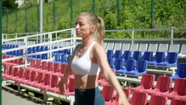 Kaukasiska vacker kvinna gör hoppa och klappa motion utomhus på idrottsplats — Stockvideo