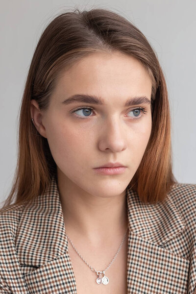 молодая привлекательная белая женщина с длинными каштановыми волосами в пиджаке в студии