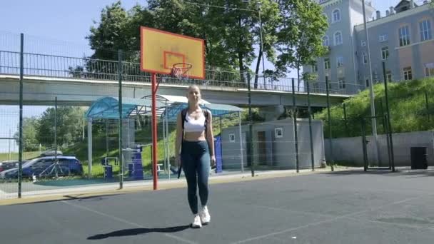 Młoda atletyczna blondynka z kucykiem w odzieży sportowej spacerująca po boisku sportowym — Wideo stockowe